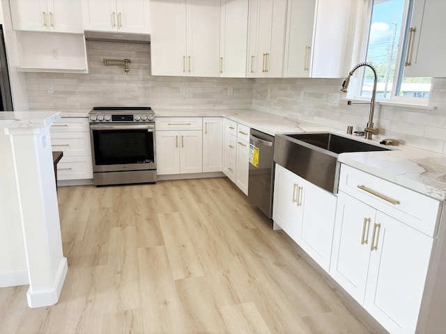 kitchen with sink, appliances with stainless steel finishes, light stone countertops, light hardwood / wood-style floors, and white cabinets