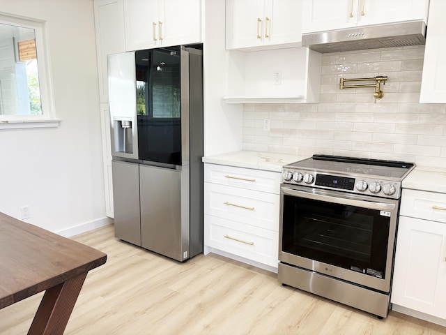 kitchen featuring white cabinetry, stainless steel appliances, light stone countertops, and light wood-type flooring