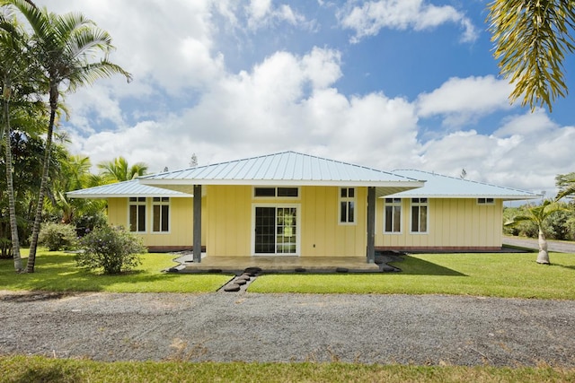 view of front of home with board and batten siding, metal roof, and a front lawn