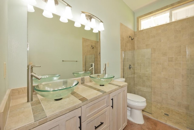 bathroom with a sink, double vanity, and a tile shower