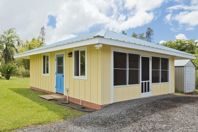 view of side of property featuring board and batten siding, a shed, metal roof, a yard, and an outdoor structure