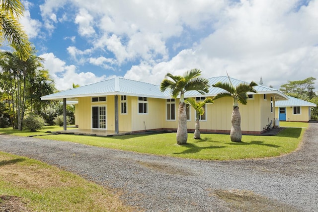 exterior space featuring gravel driveway, a front yard, and metal roof