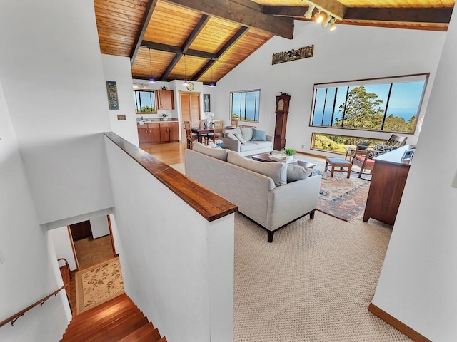 living area with high vaulted ceiling, light wood-style flooring, wood ceiling, baseboards, and beamed ceiling