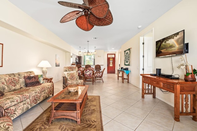 living area featuring light tile patterned floors, ceiling fan with notable chandelier, visible vents, and baseboards