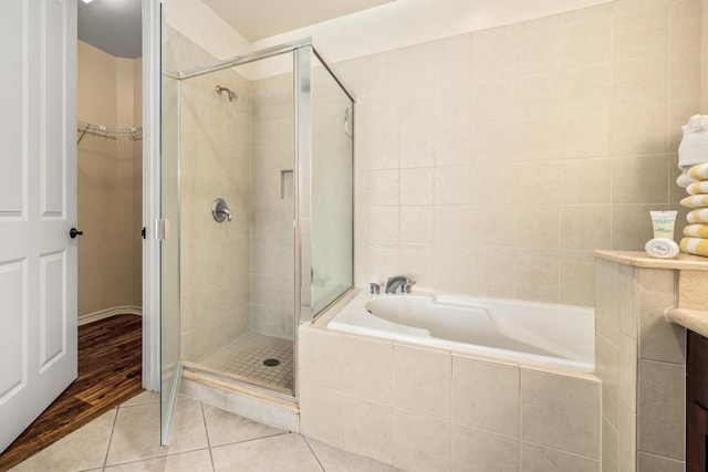 full bath with a garden tub, a spacious closet, a stall shower, and tile patterned flooring