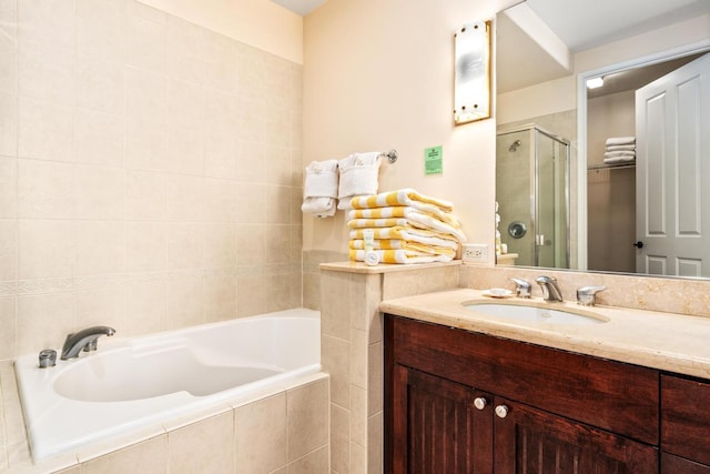 bathroom featuring a stall shower, a garden tub, and vanity