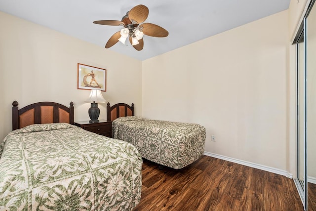 bedroom featuring a ceiling fan, a closet, baseboards, and dark wood-style flooring