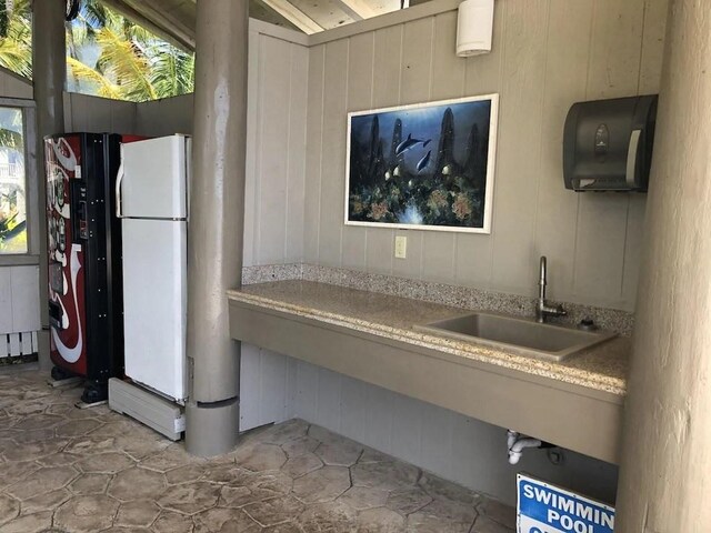 kitchen with black fridge, wooden walls, sink, and white fridge