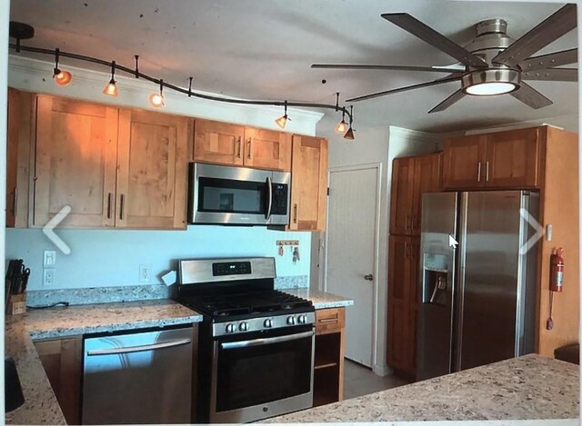 kitchen with ceiling fan, track lighting, appliances with stainless steel finishes, and light stone countertops