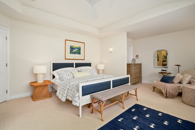 carpeted bedroom with a raised ceiling and ceiling fan