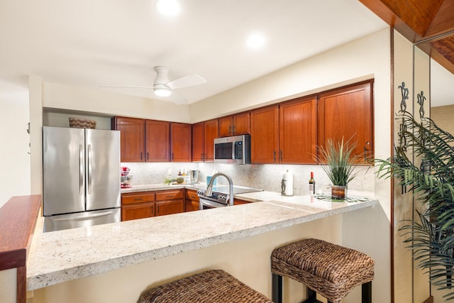 kitchen featuring backsplash, a breakfast bar area, kitchen peninsula, and appliances with stainless steel finishes