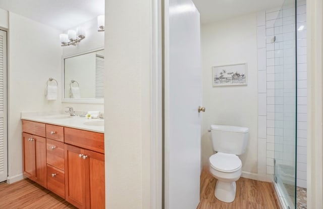 bathroom with toilet, a sink, double vanity, and wood finished floors