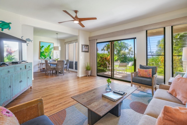 living area with light wood-style floors, baseboards, and a ceiling fan