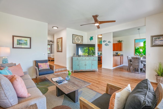 living room with a ceiling fan, light wood-style flooring, and baseboards