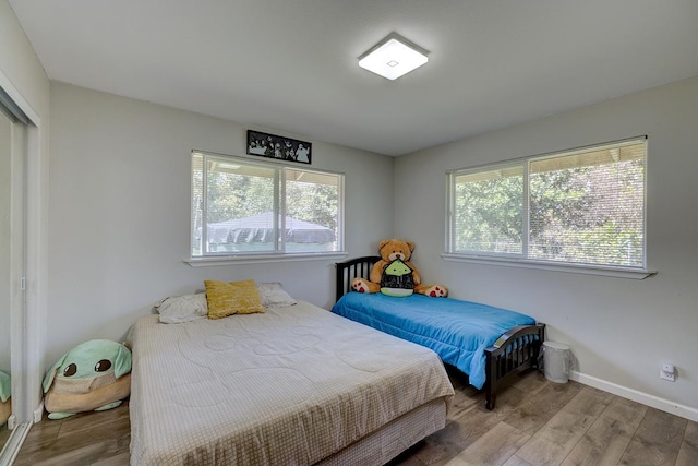 bedroom featuring a closet, wood finished floors, and baseboards