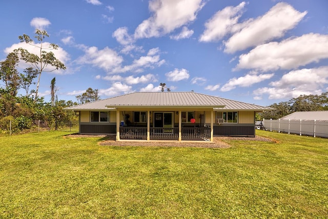 rear view of property with fence, metal roof, and a yard