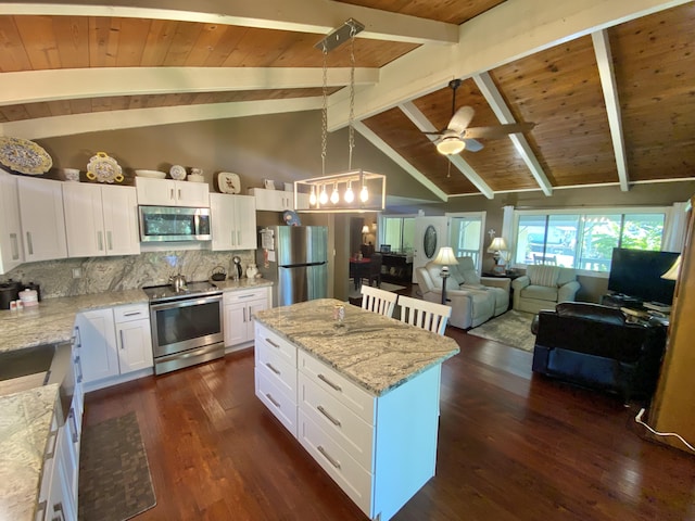 kitchen with a kitchen island, appliances with stainless steel finishes, pendant lighting, white cabinetry, and light stone countertops