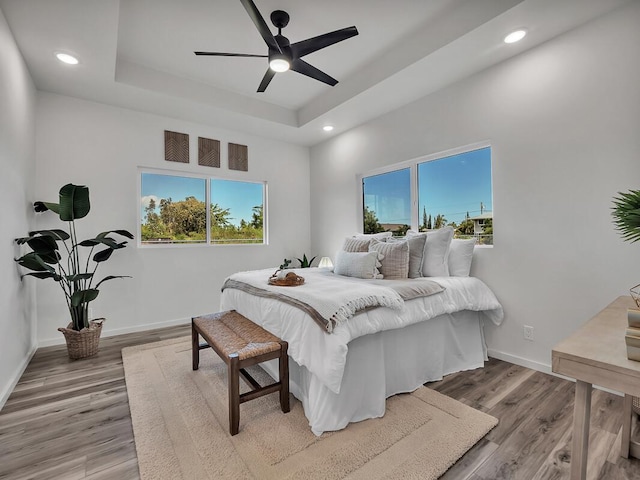 bedroom featuring ceiling fan, a raised ceiling, and hardwood / wood-style floors