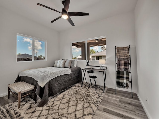 bedroom with ceiling fan, light hardwood / wood-style floors, and multiple windows