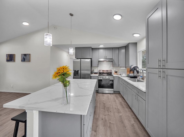 kitchen with sink, hanging light fixtures, a center island, light stone counters, and stainless steel appliances