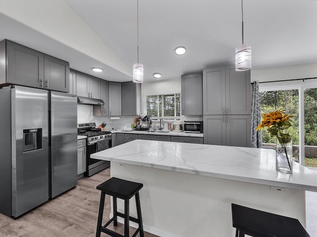 kitchen featuring stainless steel appliances, light stone countertops, hanging light fixtures, and gray cabinetry