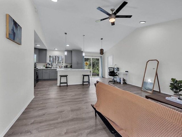 living room with lofted ceiling, hardwood / wood-style floors, and ceiling fan