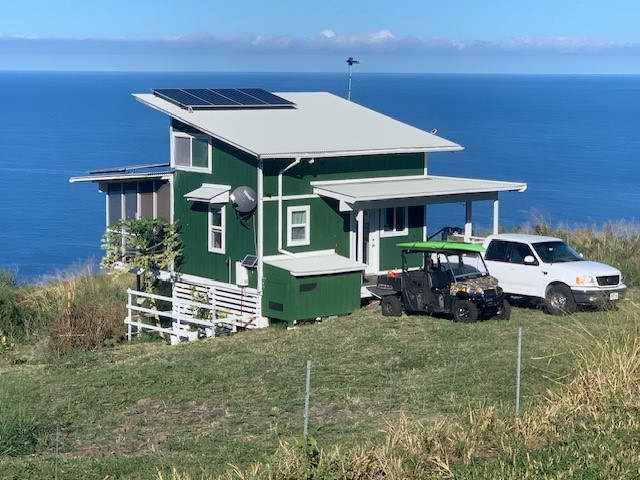 view of front of house with a front lawn, solar panels, and a water view