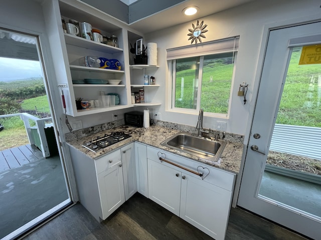 kitchen featuring dark wood-type flooring, stainless steel gas cooktop, sink, white cabinetry, and light stone countertops