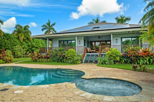 back of property with ceiling fan, a pool with hot tub, and solar panels