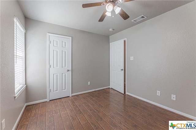 unfurnished bedroom featuring ceiling fan, dark hardwood / wood-style flooring, and multiple windows