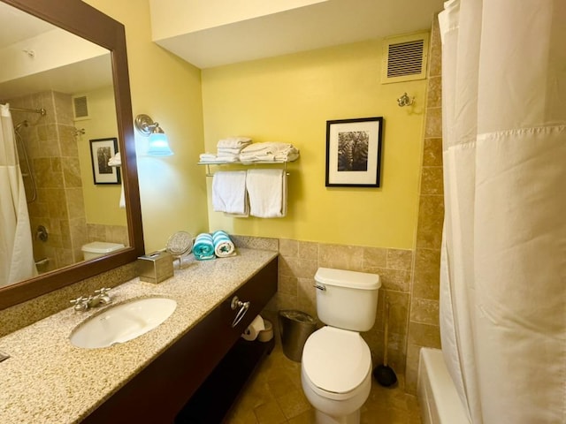 full bathroom with vanity, tile walls, shower / bathtub combination with curtain, and toilet