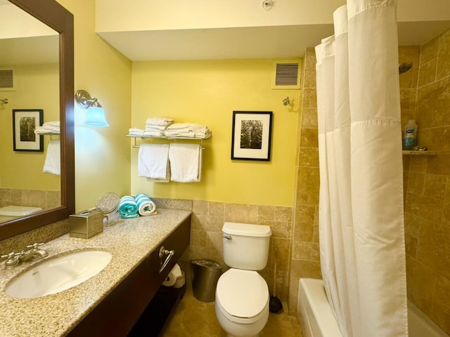 full bathroom with vanity, tile walls, shower / bath combo with shower curtain, and toilet