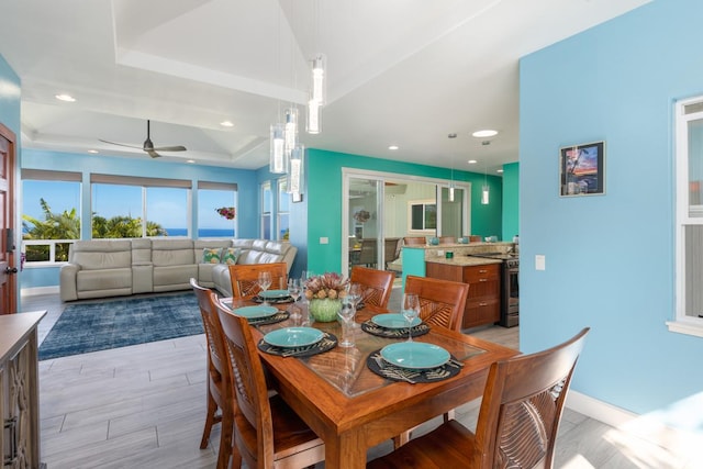 dining room with baseboards, a tray ceiling, light wood-type flooring, and recessed lighting