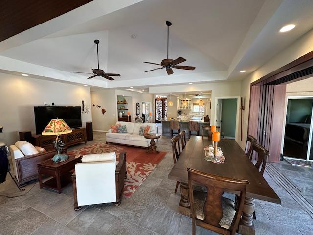 interior space with vaulted ceiling, ceiling fan, and a tray ceiling