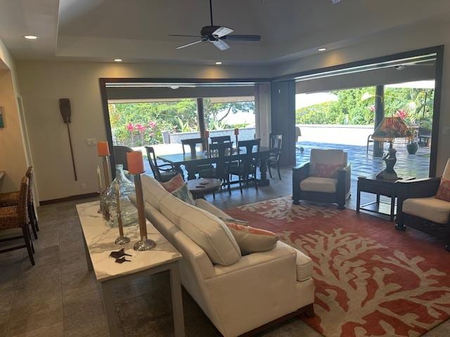 tiled living room featuring a tray ceiling and ceiling fan