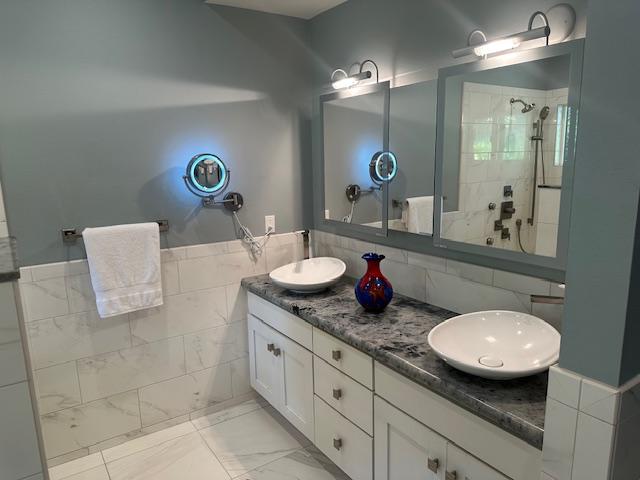 bathroom with vanity, tile walls, and a tile shower