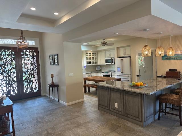 foyer entrance featuring ceiling fan and a tray ceiling