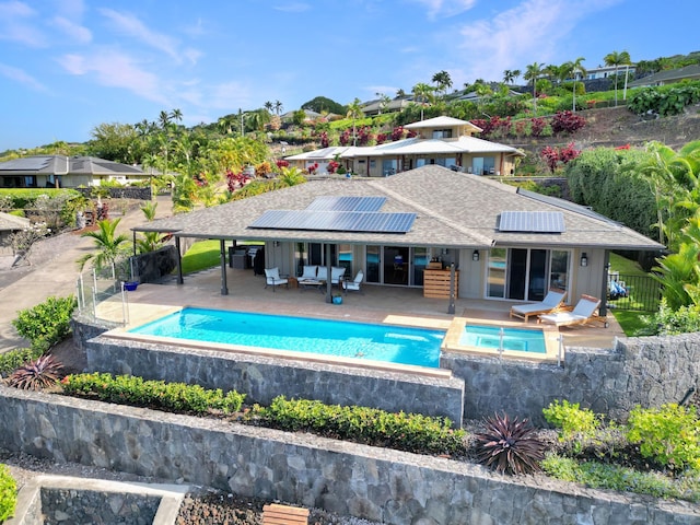 back of property with a patio, solar panels, and a swimming pool with hot tub