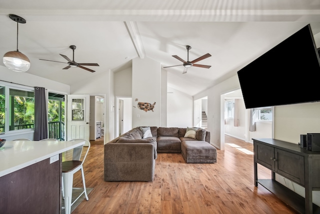 living room with ceiling fan, light hardwood / wood-style flooring, lofted ceiling with beams, and a healthy amount of sunlight