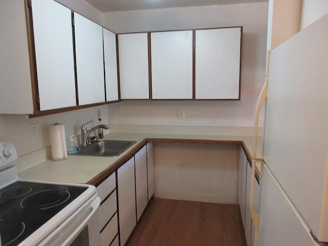 kitchen featuring light countertops, white cabinets, a sink, wood finished floors, and white appliances