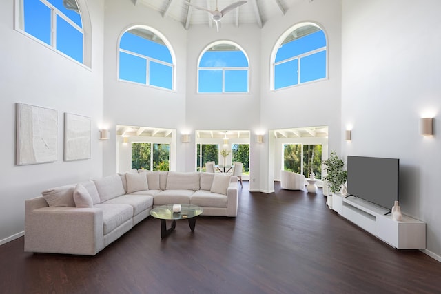 living room featuring beam ceiling, dark wood-type flooring, and a healthy amount of sunlight