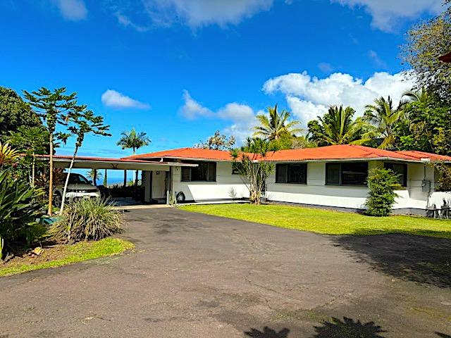 view of front of property featuring an attached carport, a front yard, and aphalt driveway