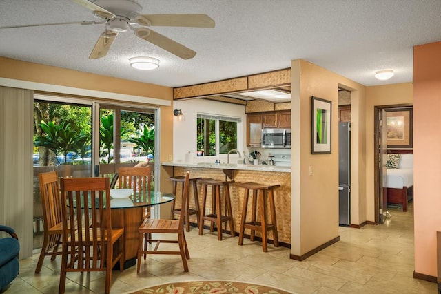 dining space with ceiling fan, sink, and a textured ceiling