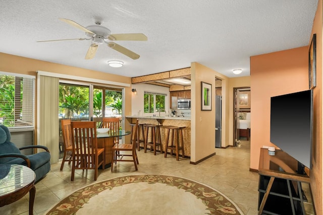 dining space with light tile patterned flooring, ceiling fan, and a textured ceiling