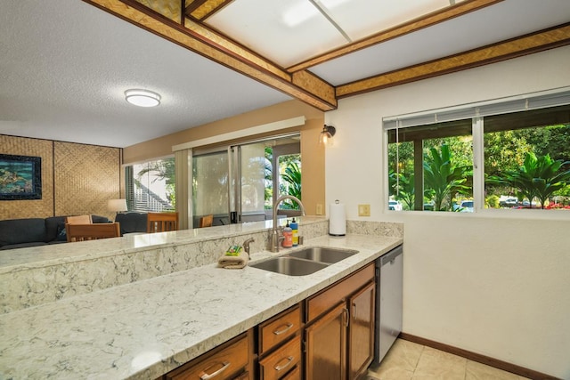 kitchen with sink, a textured ceiling, light tile patterned floors, stainless steel dishwasher, and light stone countertops