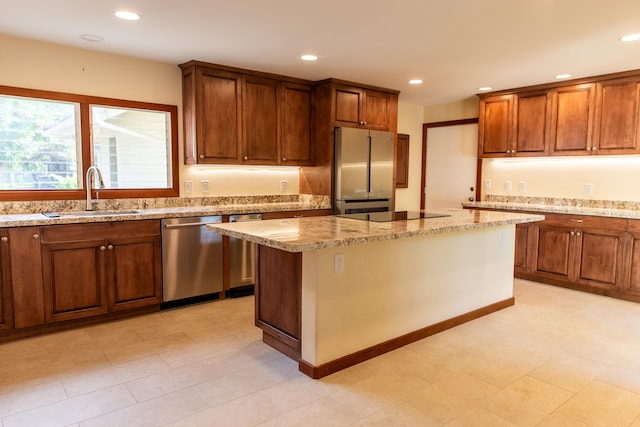 kitchen with a center island, appliances with stainless steel finishes, sink, and light stone countertops