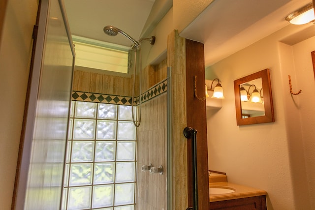 bathroom with tiled shower and vanity