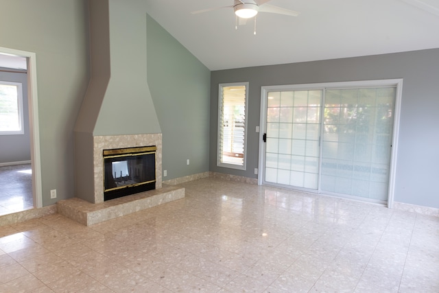 unfurnished living room featuring ceiling fan, high vaulted ceiling, a premium fireplace, and a wealth of natural light