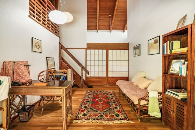 interior space featuring beam ceiling, high vaulted ceiling, and wood finished floors