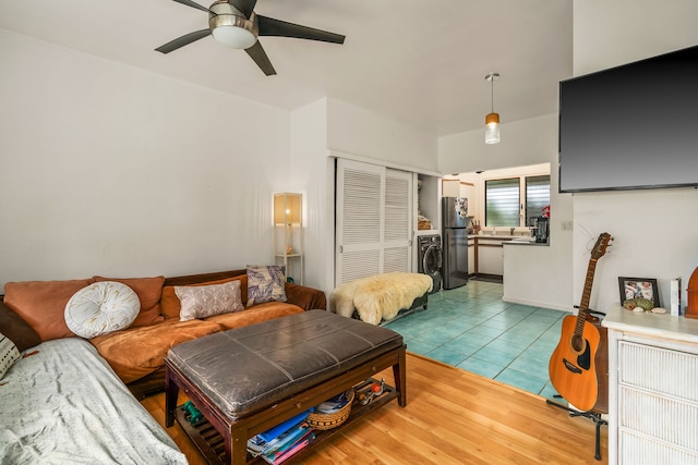 living area with washer / dryer, light tile patterned flooring, and a ceiling fan